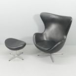 A black leather upholstered egg chair and footstool in the manner of Arne Jacobsen.
