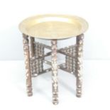 A Ugandan brass tray top table, on folding hardwood base with inlaid mother-of-pearl decoration.