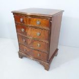 A reproduction crossbanded mahogany serpentine-front chest of four drawers on bracket feet.