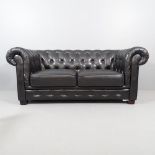 A black button back faux-leather upholstered two seater Chesterfield sofa. Overall 188x80x90cm, seat