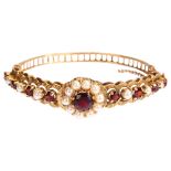 A mid-20th century 9ct gold garnet and pearl cluster hinge bangle, with central flowerhead cluster