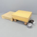 A Japanese Go set comprising two pots of counters and wooden board. 46x25x43cm.
