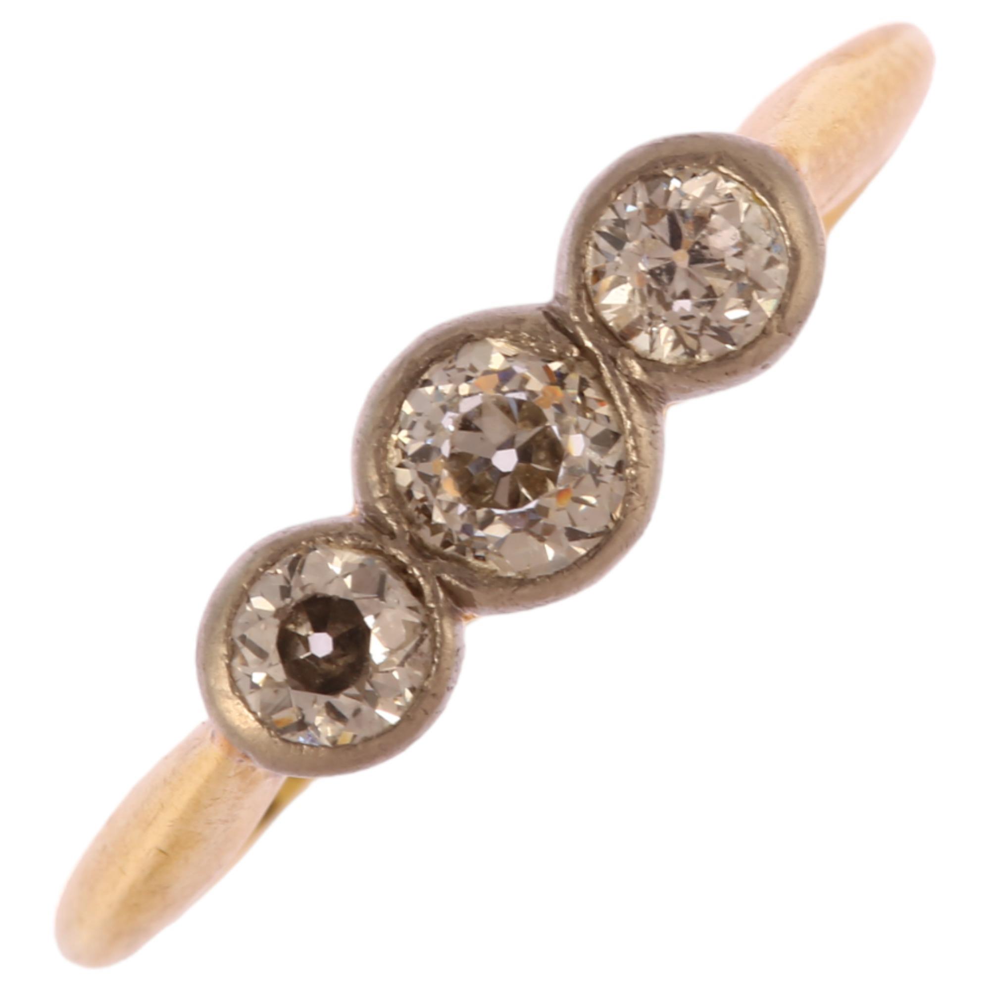 An early 20th century 18ct gold three stone diamond ring, bezel set with old European cut