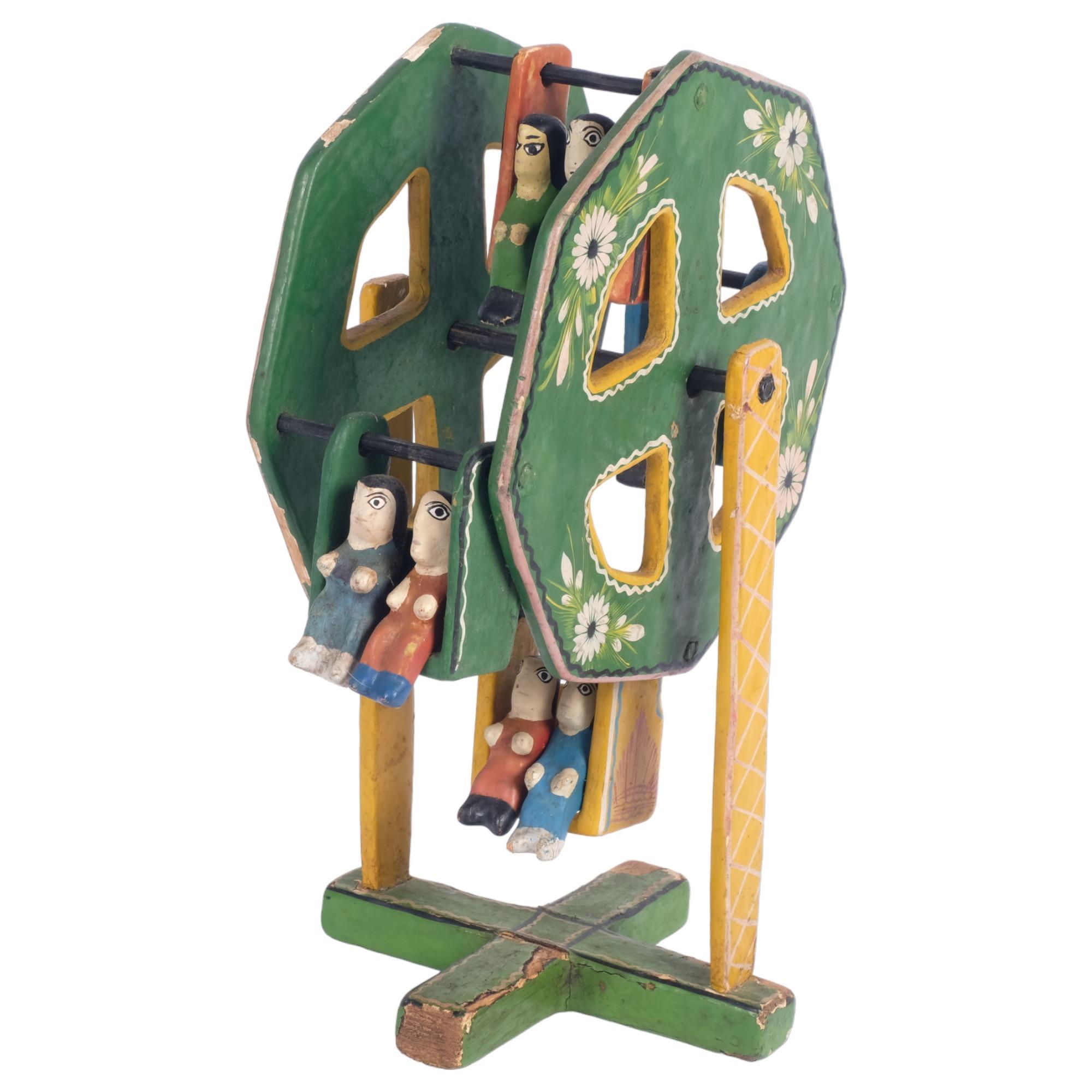 An unusual Mexican Folk Art painted ferris wheel, complete with 4 swing seats and figures, H31cm