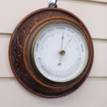 An Edwardian carved oak-cased combination aneroid barometer with thermometer, diameter 20cm