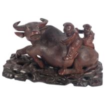 A Chinese carved wood hardwood figural group of 2 boys climbing on the back of a water buffalo,