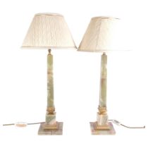 A pair of onyx and gilt-metal mounted table lamps and shades, height to top of bayonet fitting 54cm