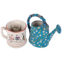 Enamelled ceramic watering can with floral decoration, 20.5cm, and a painted pottery frog mug