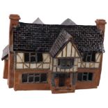 A handmade and glazed pottery lamp, in the form of a Tudor house, 31cm across