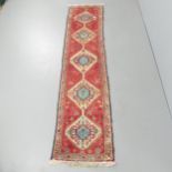 A red-ground Afghan runner. 255x60cm.