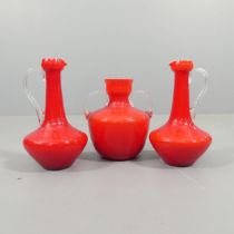 A mid-century pair of red Murano glass pitchers, height 30cm, and a matching vase, Height 25cm. (3)