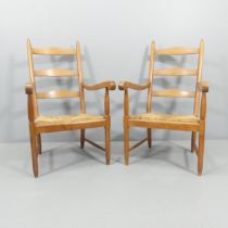 An unusual pair of Cotswold School Arts and Crafts ladderback lounge chairs in oak with rush seats.