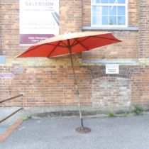 A Garden parasol on cast iron base. Diameter approximately 275cm, height 235cm. Good used condition.