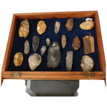 A museum display of flint hand axes, spearheads, petrified wood specimen etc, in glazed pine display