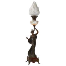 An Art Nouveau oil lamp, supported by a bronze patinated spelter figure of a woman, lustre glass