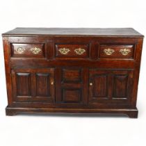 An 18th century panelled oak dresser base, circa 1700, with 3 fielded frieze drawers, 2 panelled