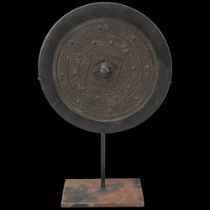 A Chinese relief cast bronze mirror, diameter 19cm, on modern metal stand