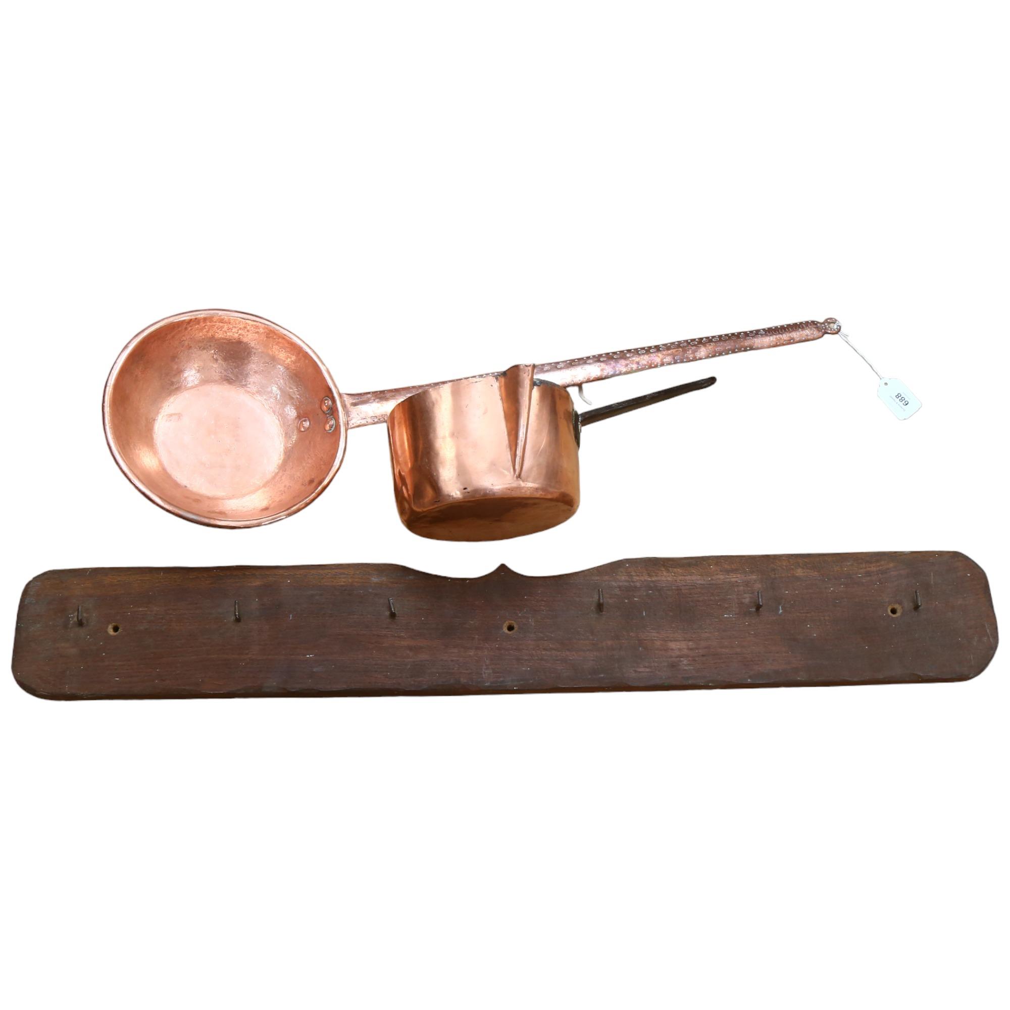 A long-handled copper pan, 77cm, a copper milk pan, and coat hooks