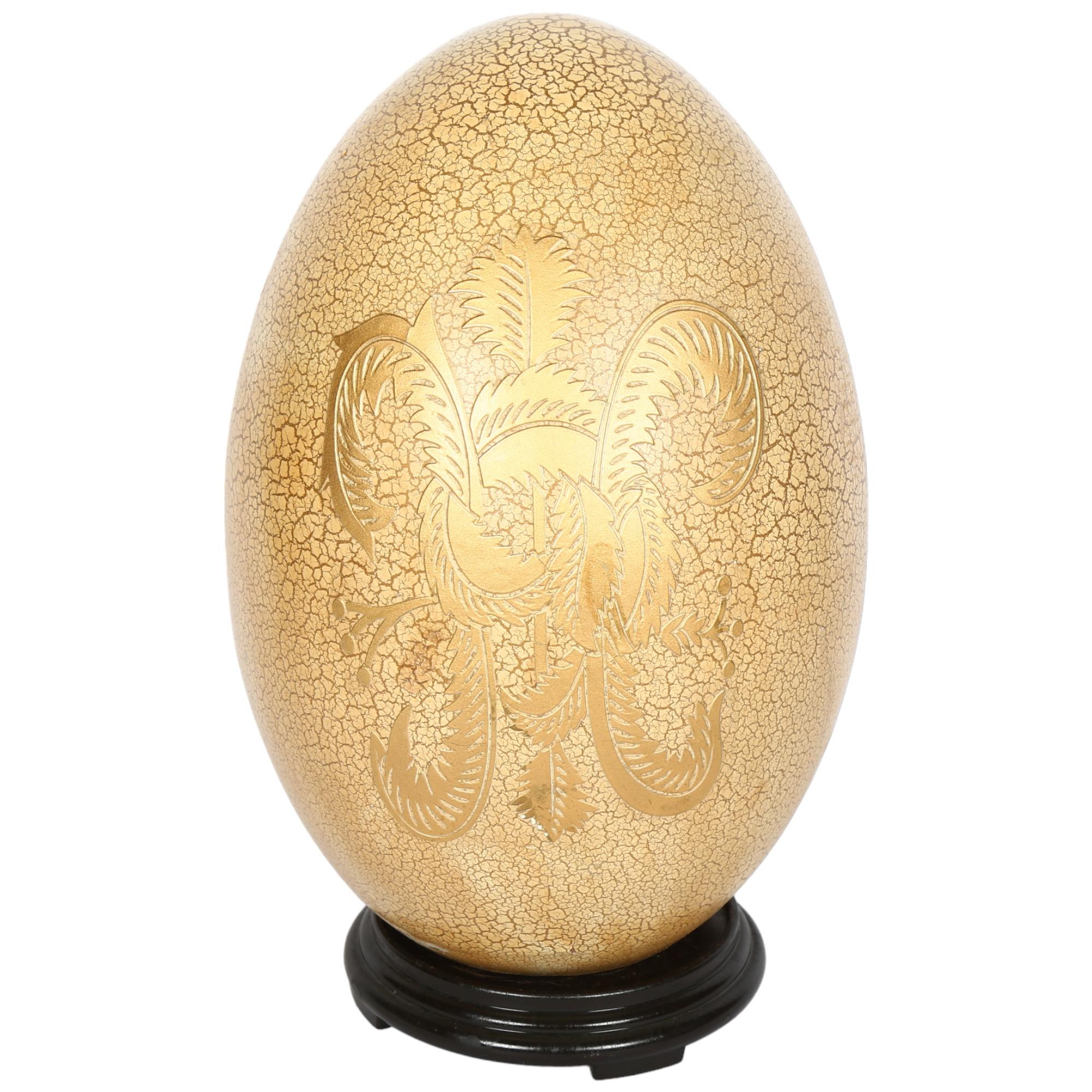 An ornamental gilded ceramic egg on stand, H36cm