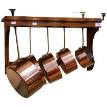 A graduated set of 5 French copper steel and brass-handled pans, and stained pine hanging rack,