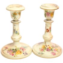 A pair of Royal Worcester Blush Ivory candlesticks, with painted floral spray and gilded decoration,