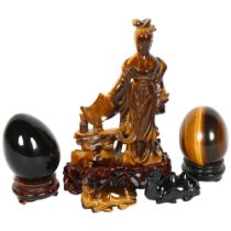 A tigers eye Goddess on associated wooden stand, H16cm, a tigers eye egg on associated wooden stand,