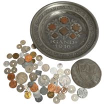 A pewter plate with various coins embossed to the middle section, and a quantity of various other