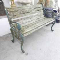 A weathered teak slatted garden bench with cast iron ends. 130x83x65cm.