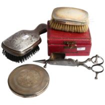 A Mexican silver compact, a cased silver-mounted brush, another, and a pair of plated candle