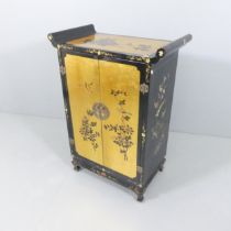 A contemporary Oriental black lacquered two door cabinet, with gilt painted and gold leaf