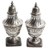 A pair of embossed silver pepperettes on square bases, hallmarks for London 1895