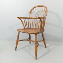 An elm-seated comb-back Windsor elbow chair, with crinoline stretcher. One spindle broken to back