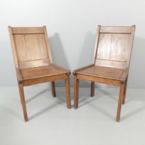 A pair of stained pine side chairs with panelled backs.