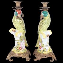 A pair of ceramic parrot figure candlesticks, with ornate brass mounts