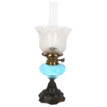 A Victorian oil lamp, with etched frilled shade and blue font, on embossed cast-iron base, overall