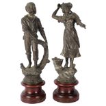A pair of Continental patinated spelter figures, with fishing nets and basket, on turned wood