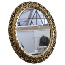 A large wooden oval wall-hanging bevel-edge mirror, in ornate giltwood frame, 76cm x 63cm