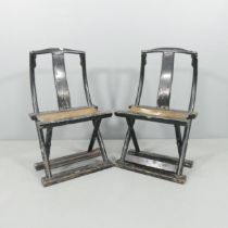 An antique pair of Chinese black lacquered folding chair, with hardwood frames and woven seats.