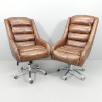 A pair of mid-century style leather upholstered swivel lounge chairs on chrome star bases, with rise