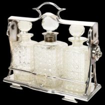 A plated 3-bottle tantalus, circa 1900, containing 3 square cut-glass decanters, 1 with hallmarked