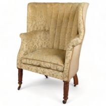 A 19th century upholstered barrel-back wing armchair on turned legs, overall width 76cm, height