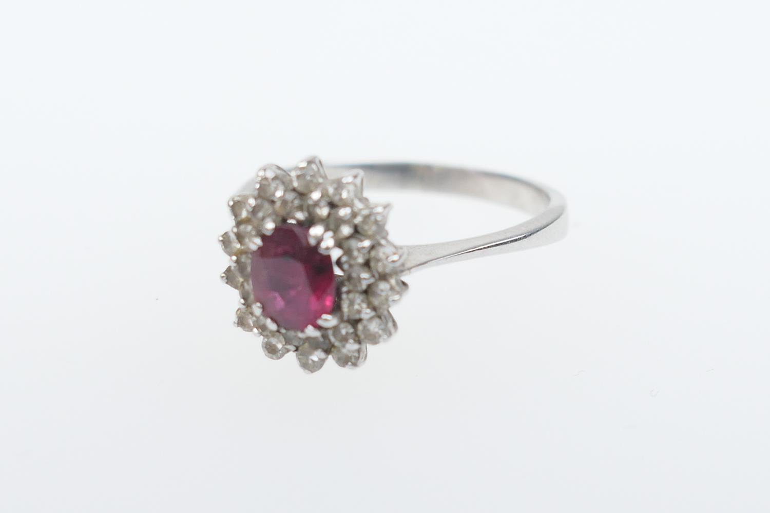 Ruby and diamond cluster ring, the oval cut ruby of approx. 1ct, bordered with small round cut