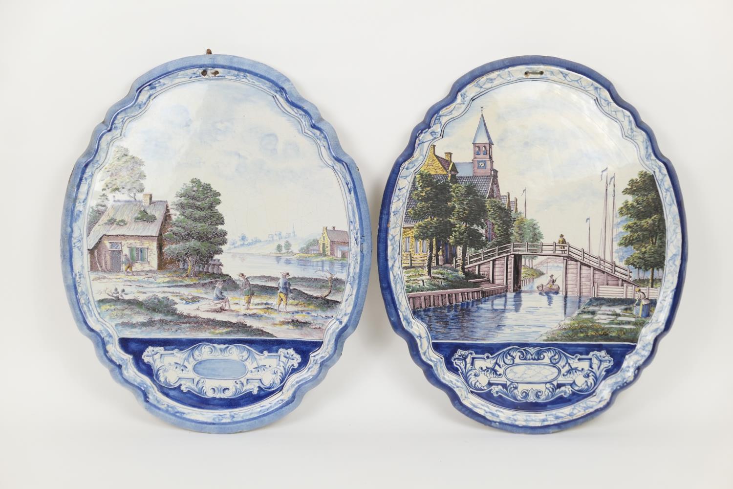 Two Makkum faience wall plaques, one featuring a canal scene, the other figures beside a river, both