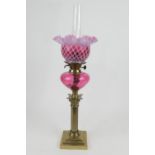 Victorian brass and cranberry glass pedestal oil lamp, frilled white and cranberry lattice shade