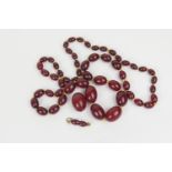 Cherry amber oval bead necklace, having individually knotted graduating beads, the largest bead