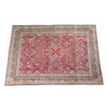 Kirman carpet, the red field dispersed with foliage and flowerheads within a blue and fawn border of