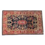 Kashan rug, having a central elongated red reserve against a deep blue ground dispersed with flowers