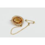 Citrine and pearl brooch, the oval stone 18mm x 10mm, in a millegrain collet mount, bordered with