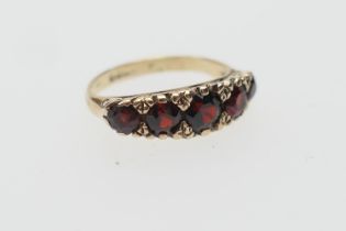 Garnet five stone ring, the graduated round cut stones in scroll mounts on a 9ct gold hallmarked