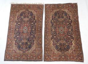 Pair of Persian Kashan woollen rugs, centred with a red and fawn medallion against a deep blue field